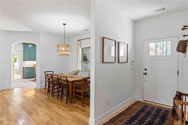 entryway featuring light wood-type flooring, baseboards, and arched walkways