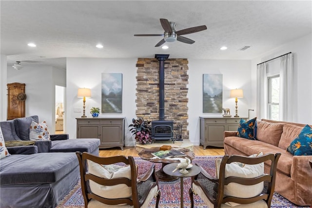 living area with light wood finished floors, visible vents, ceiling fan, a wood stove, and recessed lighting