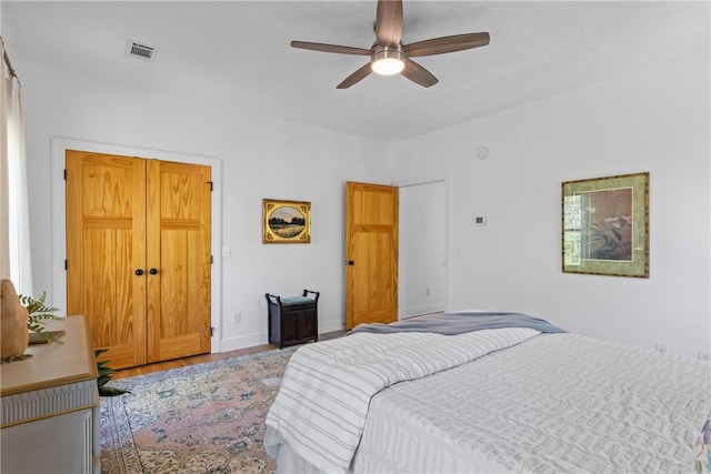 bedroom featuring baseboards, a ceiling fan, visible vents, and wood finished floors