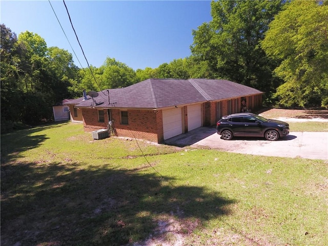 26 Arrowhead Rd, Phenix City, AL 36869 - view of side of property featuring driveway, an attached garage, central air condition unit, brick siding, and a yard