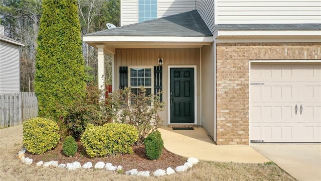 property entrance featuring a garage, brick siding, a shingled roof, and fence