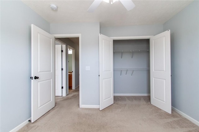 unfurnished bedroom featuring a closet, light colored carpet, a textured ceiling, and baseboards