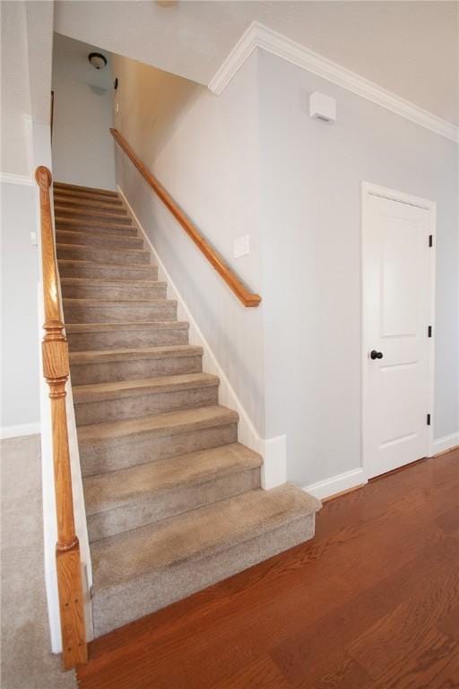 stairs featuring baseboards, wood finished floors, and crown molding