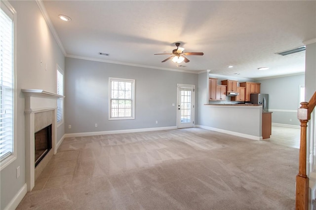 unfurnished living room featuring visible vents, baseboards, light colored carpet, and crown molding