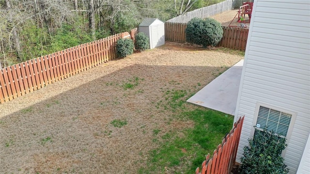 view of yard with a fenced backyard, a storage unit, and an outdoor structure