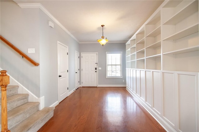 foyer entrance featuring crown molding, stairway, wood finished floors, and baseboards