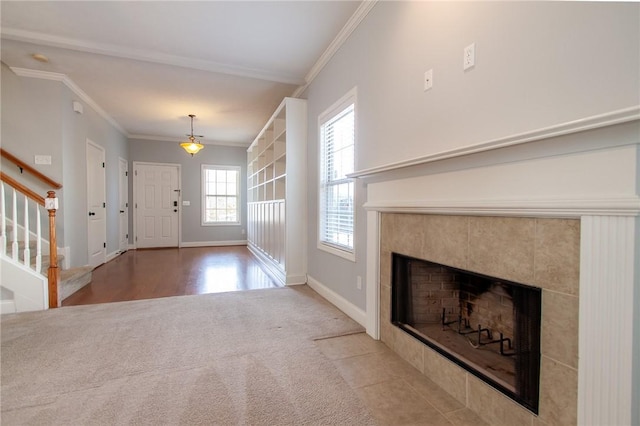 carpeted foyer entrance with stairway, baseboards, crown molding, and a tile fireplace