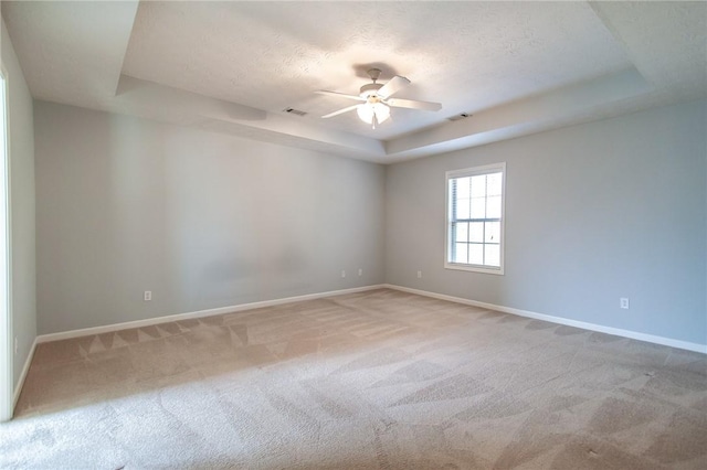 carpeted spare room with baseboards, visible vents, ceiling fan, a textured ceiling, and a raised ceiling