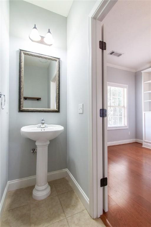 bathroom featuring tile patterned floors, visible vents, baseboards, and ornamental molding