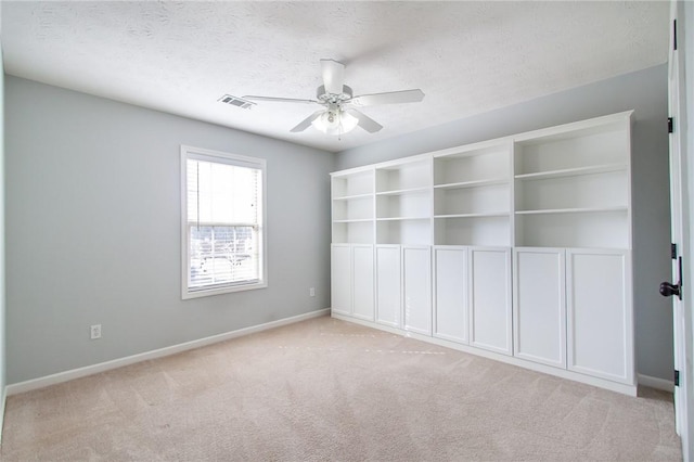 empty room featuring visible vents, a textured ceiling, carpet, baseboards, and ceiling fan