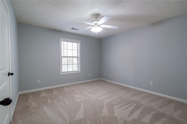 spare room with visible vents, light carpet, a textured ceiling, and baseboards