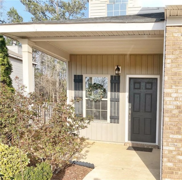 doorway to property featuring covered porch and brick siding