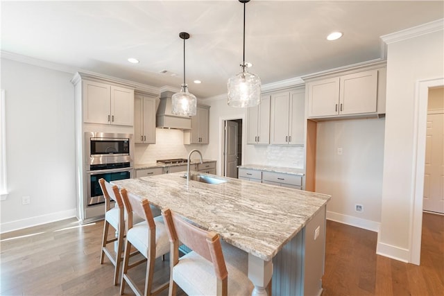 kitchen with a center island with sink, sink, premium range hood, and stainless steel appliances