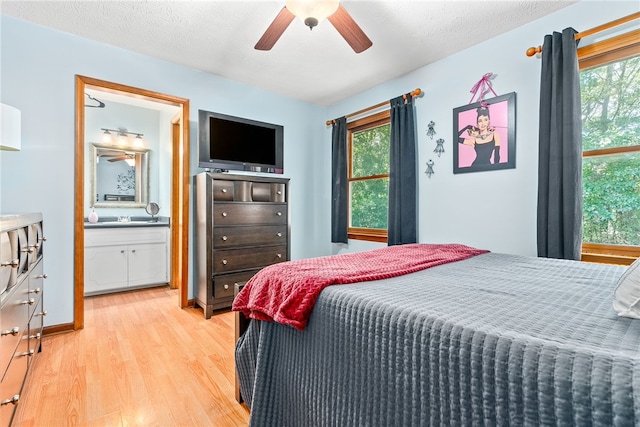 bedroom with multiple windows, ceiling fan, ensuite bathroom, and light hardwood / wood-style floors