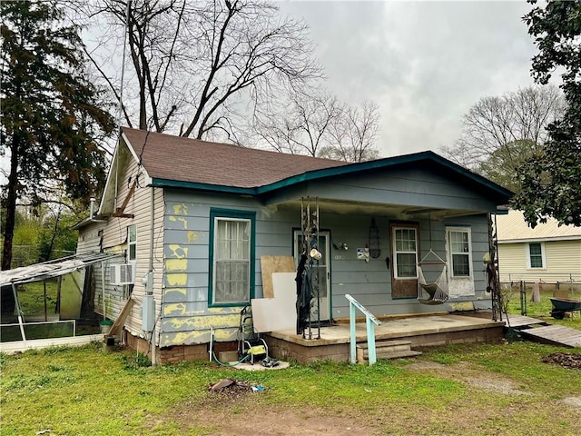 bungalow-style home with a porch, a front lawn, and a shingled roof