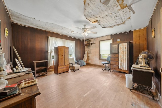 living area featuring wood finished floors, wood walls, and a ceiling fan