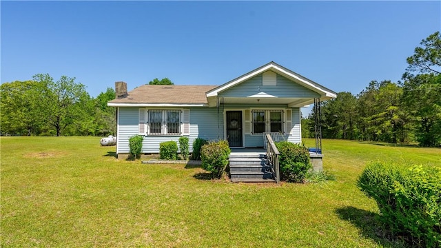 bungalow-style home with a front lawn, covered porch, and a chimney
