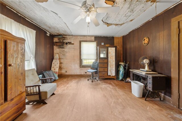 sitting room featuring wood walls, a ceiling fan, and wood finished floors