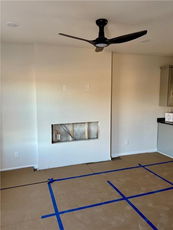 unfurnished living room with a ceiling fan, basketball court, and baseboards