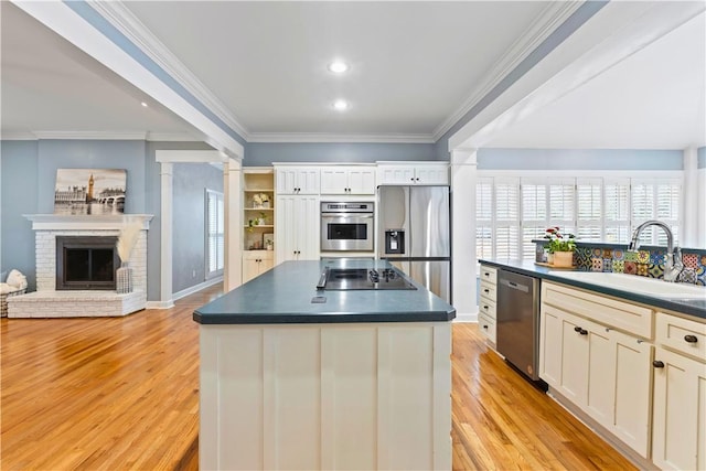 kitchen featuring dark countertops, a sink, appliances with stainless steel finishes, and crown molding