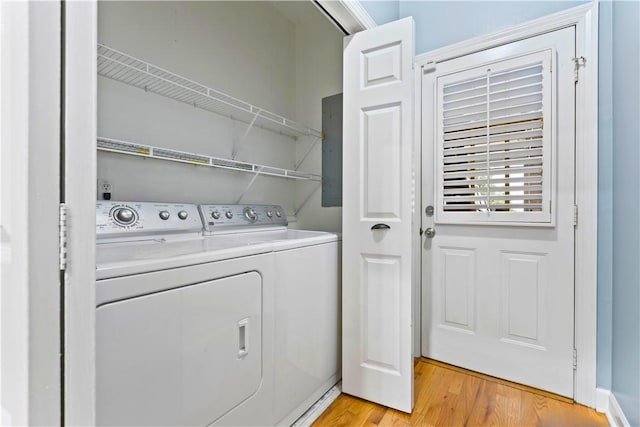 laundry area with light wood-type flooring, electric panel, laundry area, and independent washer and dryer