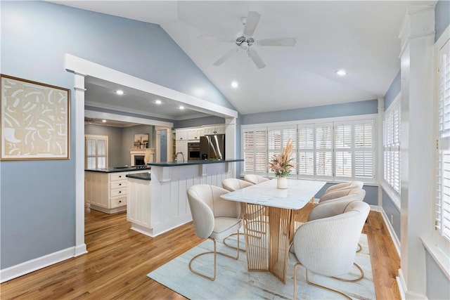 dining area with high vaulted ceiling, light wood-type flooring, baseboards, and ceiling fan
