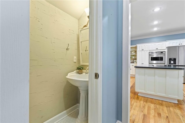 bathroom with wood finished floors and crown molding