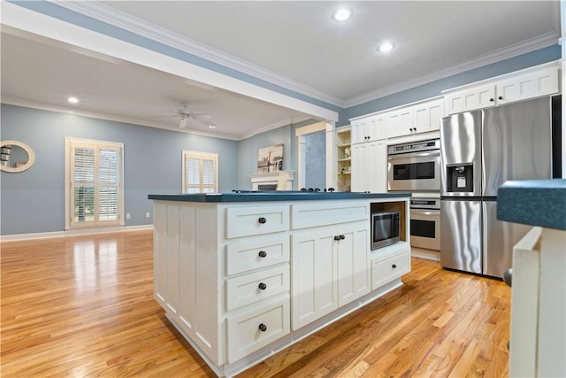 kitchen with dark countertops, appliances with stainless steel finishes, crown molding, and light wood-style floors