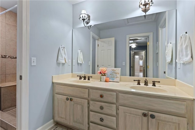 bathroom with baseboards, a sink, double vanity, and tiled shower