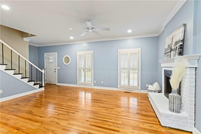 unfurnished living room with light wood-type flooring, a wealth of natural light, stairs, and ornamental molding