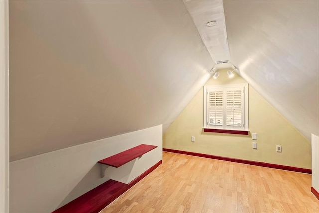 bonus room featuring light wood-style floors, lofted ceiling, and baseboards