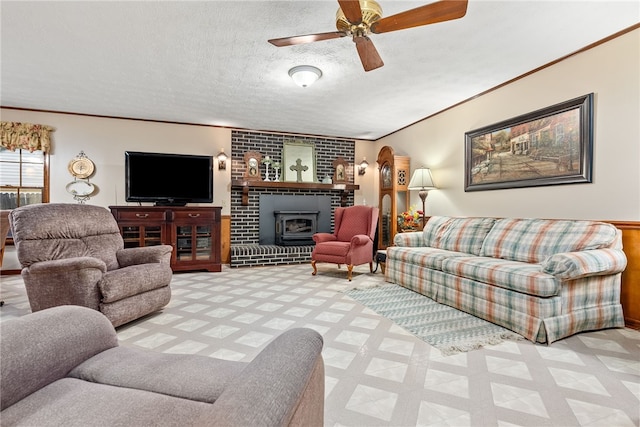 living room featuring a wood stove, ceiling fan, a textured ceiling, and ornamental molding