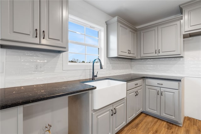kitchen with a sink, light wood-type flooring, tasteful backsplash, and gray cabinetry