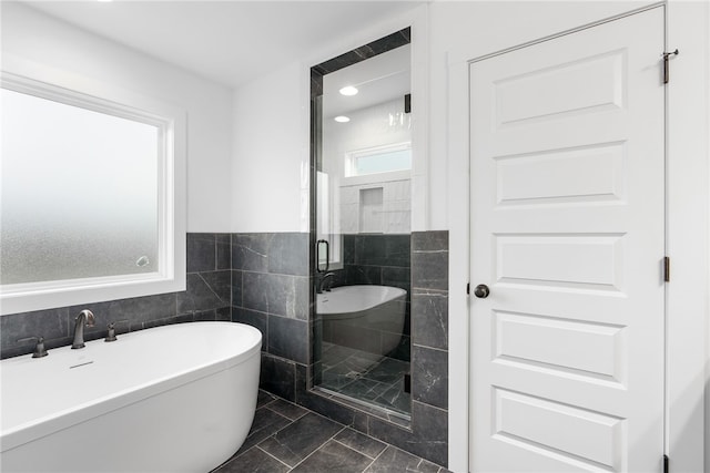 full bath with a soaking tub, tile walls, wainscoting, and a shower stall