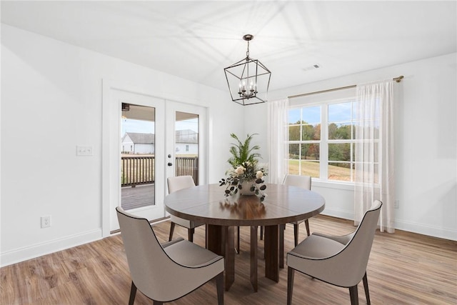 dining space with visible vents, baseboards, light wood-style flooring, french doors, and a notable chandelier
