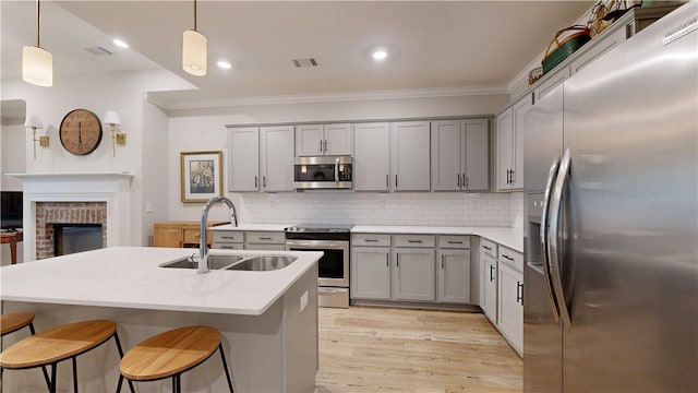 574 Grey Oak Cir, Auburn, AL 36830 - kitchen featuring appliances with stainless steel finishes, gray cabinets, crown molding, a breakfast bar area, and light wood-type flooring