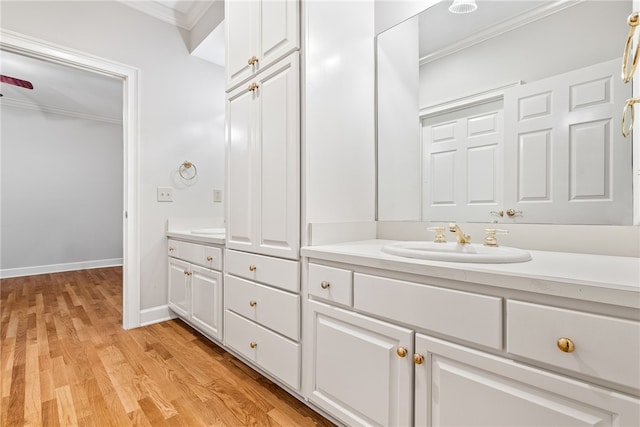 bathroom featuring wood-type flooring, vanity, and ornamental molding