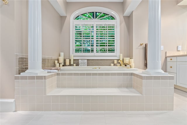 bathroom with tile patterned floors, vanity, tiled bath, and decorative columns