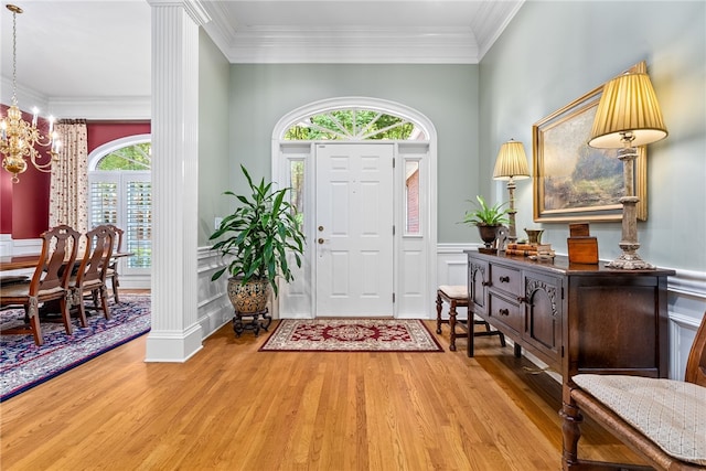 foyer entrance with a chandelier, light wood-type flooring, and ornamental molding