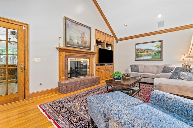 living room featuring a brick fireplace, ornamental molding, vaulted ceiling, light hardwood / wood-style flooring, and built in features