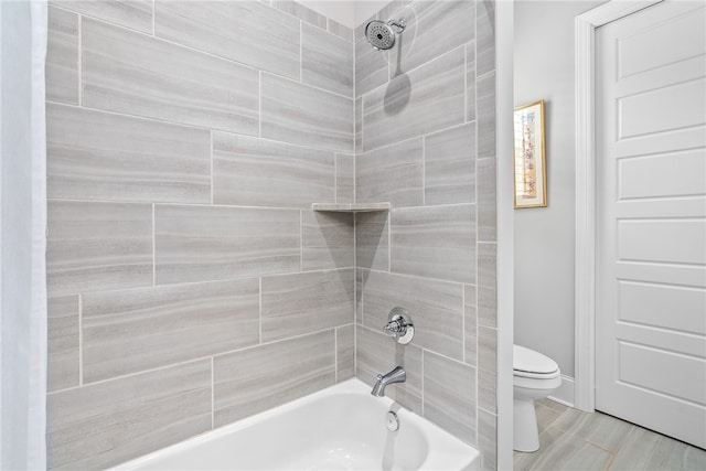 bathroom with tiled shower / bath combo and toilet