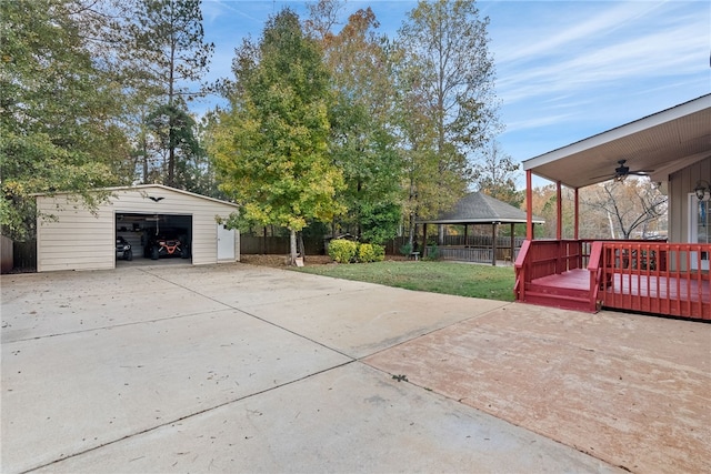 view of patio featuring a deck, an outdoor structure, ceiling fan, a gazebo, and a garage