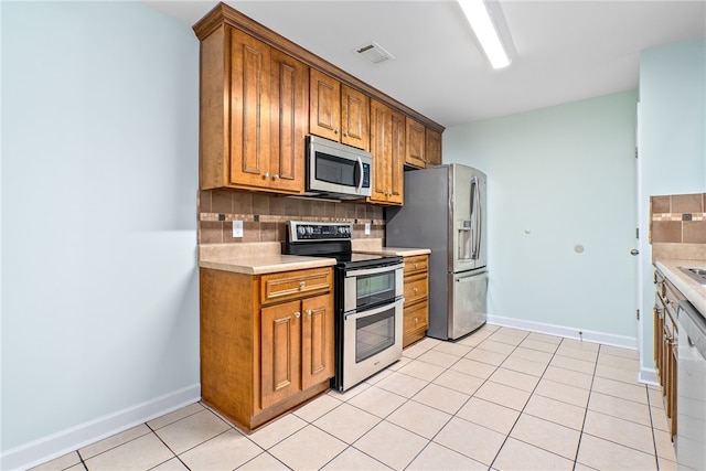 kitchen featuring decorative backsplash, light tile patterned floors, and appliances with stainless steel finishes