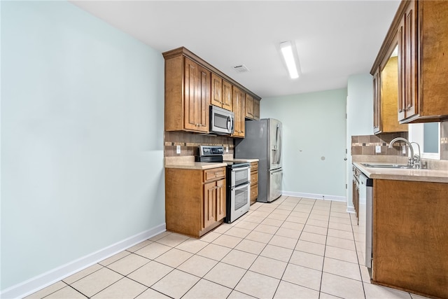 kitchen with backsplash, sink, light tile patterned floors, and stainless steel appliances