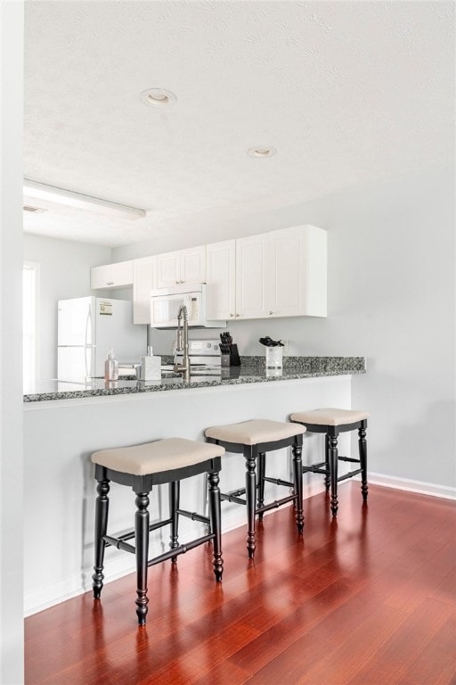 1477 N Donahue Dr N Unit 1602, Auburn, AL 36830 - kitchen featuring white appliances, dark wood-style floors, a peninsula, baseboards, and recessed lighting