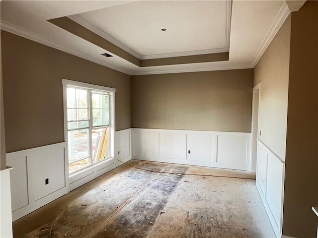 empty room with ornamental molding and a raised ceiling