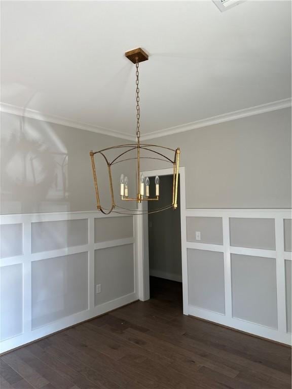 unfurnished dining area with dark wood-style floors, a decorative wall, and crown molding