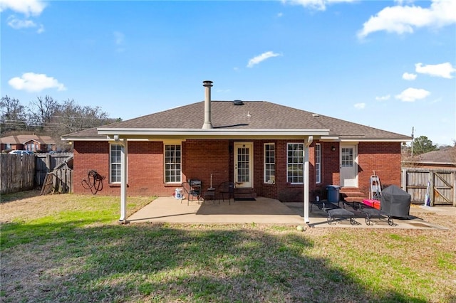 back of house featuring a fenced backyard, a patio, and brick siding