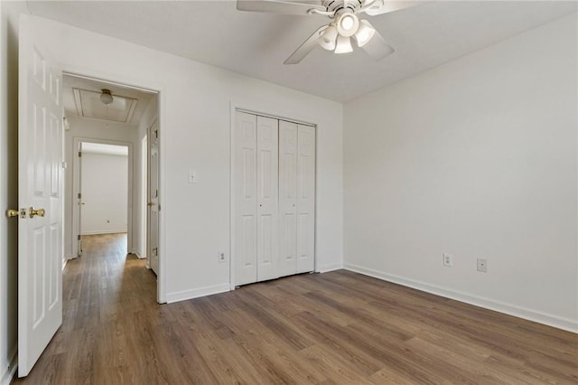 unfurnished bedroom featuring attic access, a closet, baseboards, and wood finished floors