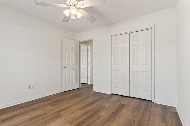 unfurnished bedroom with dark wood-style floors, a ceiling fan, baseboards, and a closet